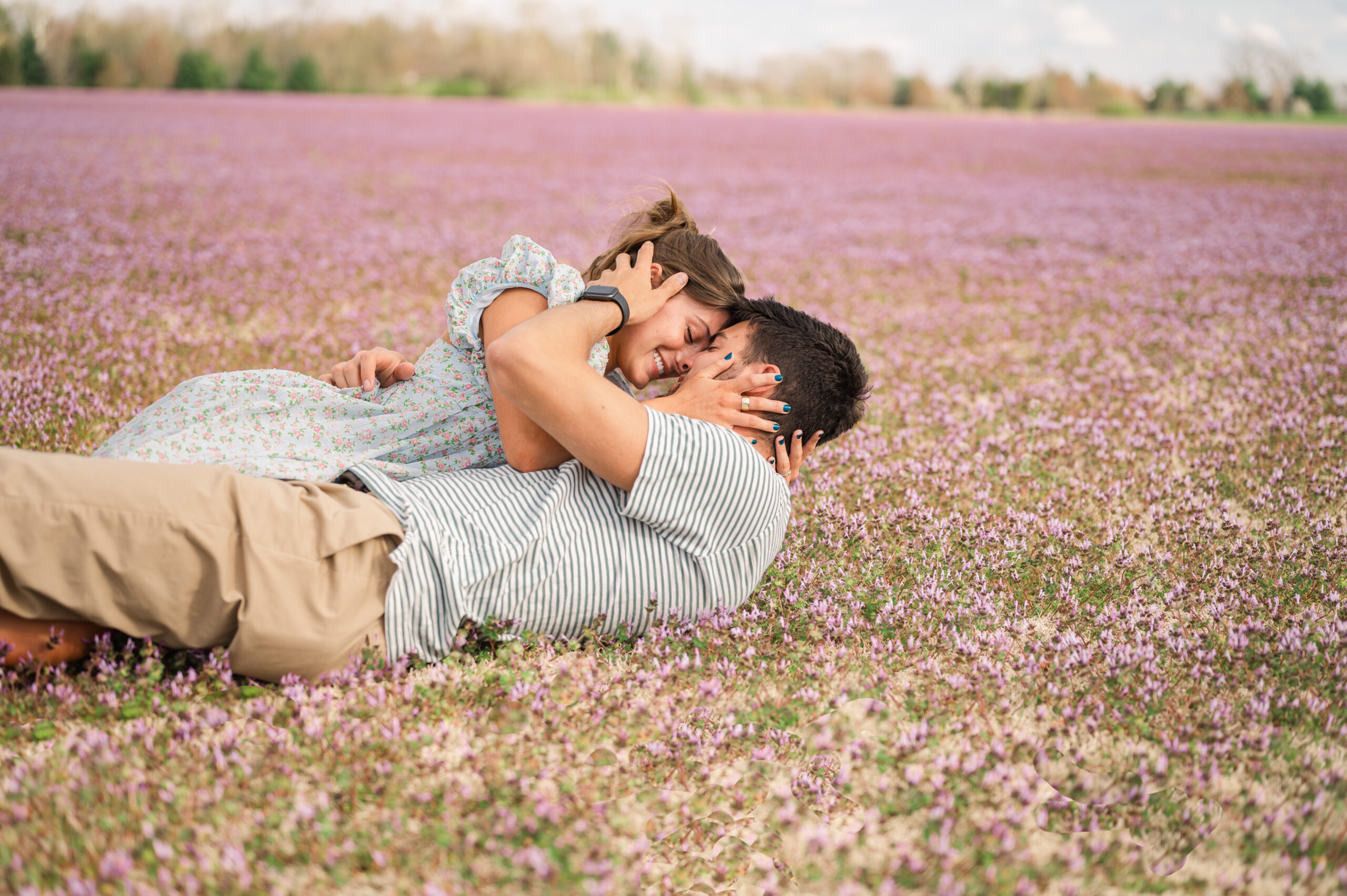 A couple shares a kiss laying in a field of purple flowers at the Kentucky Horse park